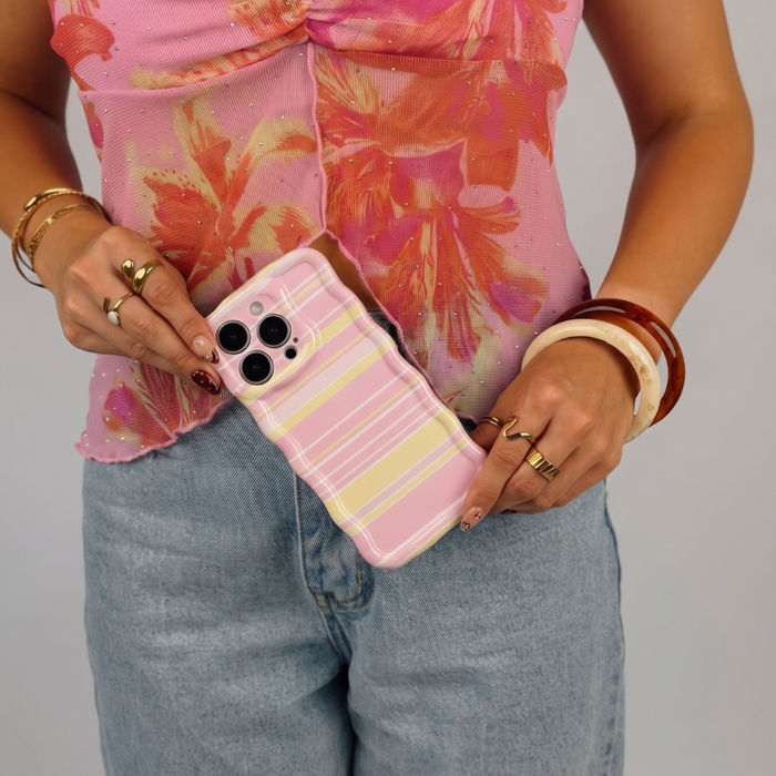 Woman holding an iphone in a pink, white and yellow horizontal striped wavy phone case.