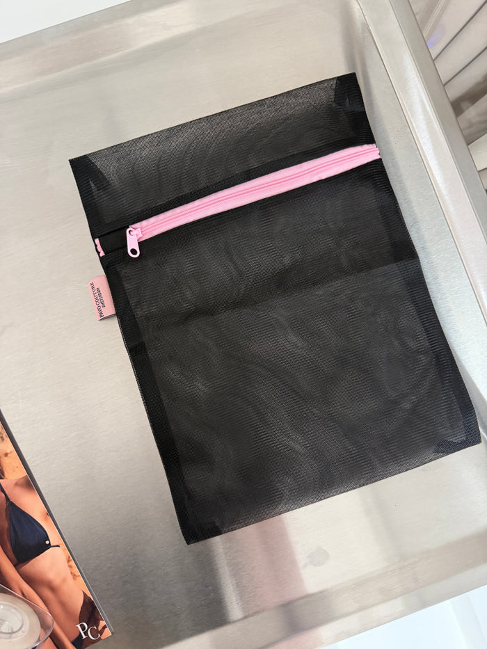 zwart waszakje roze rits op zilveren tafel