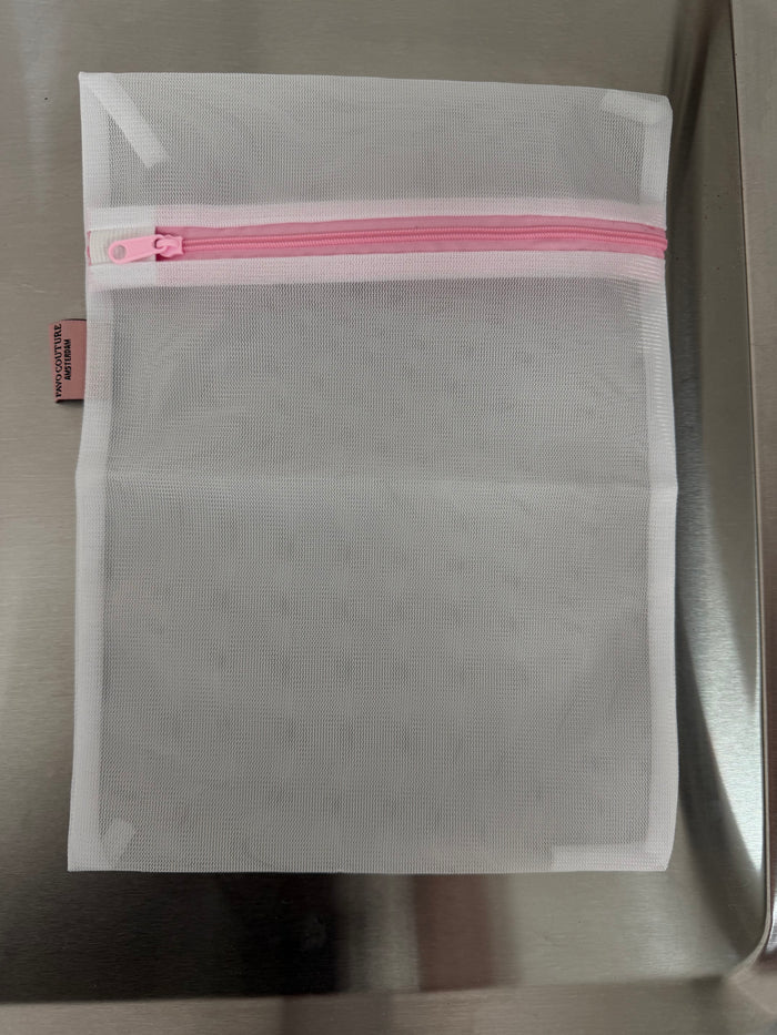 een mesh wit lingerie zakje voor de was met roze rits