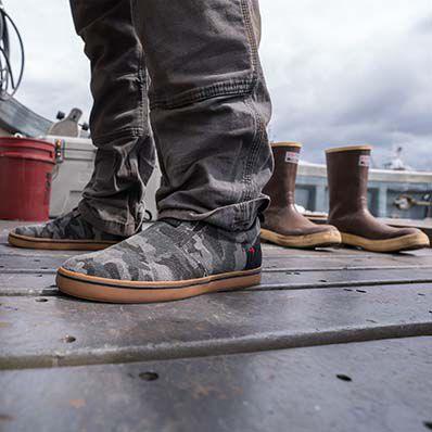 Xtratuf camo canvas Sharkbyte deck shoe shown worn on a boat deck