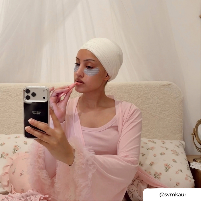 Woman taking a selfie, applying lipbalm, holding an iphone in a mirrored phone case with the text "don't call just text" printed on the back.