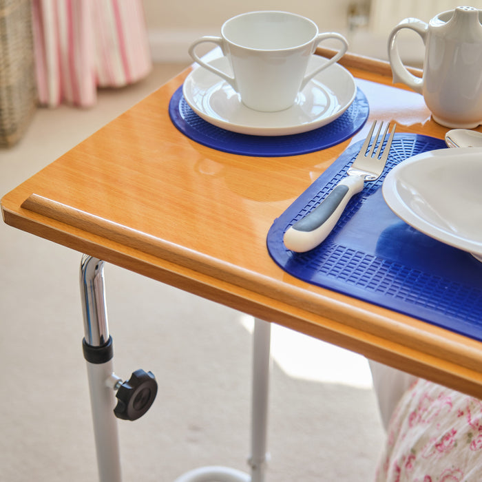 Close-up of hands adjusting the height or tilt of NRS Overbed Table, showing the easy-turn knobs.